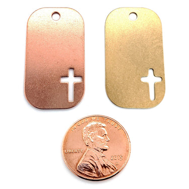 Copper and brass blank cross cutout dog tag pendants with a penny for scale.