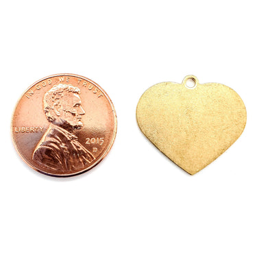 Brass blank holed heart pendant with a penny for scale.