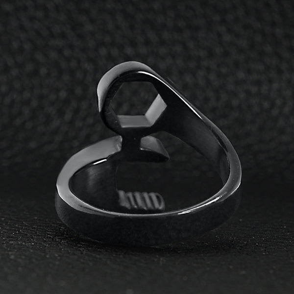 Stainless steel black wrench ring back view on a black leather background.