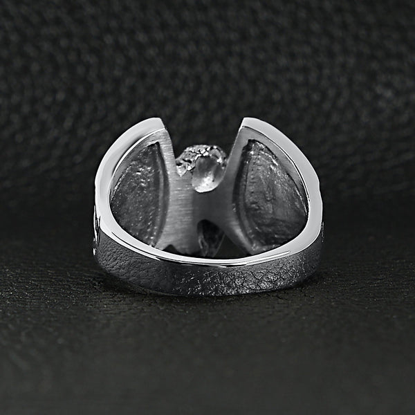 Stainless steel polished winged wheel ring back view on a black leather background.