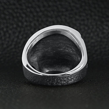 Stainless steel polished skull with cigar ring back view on a black leather background.