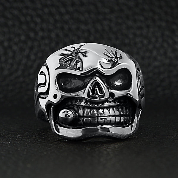 Stainless steel polished skull with cigar ring on a black leather background.