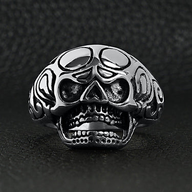 Stainless steel polished filigree skull ring on a black leather background.