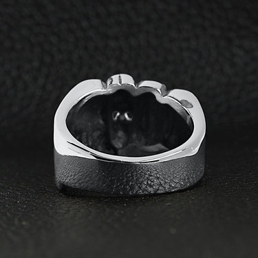 Stainless steel biker rings fist ring back view on a black leather background.