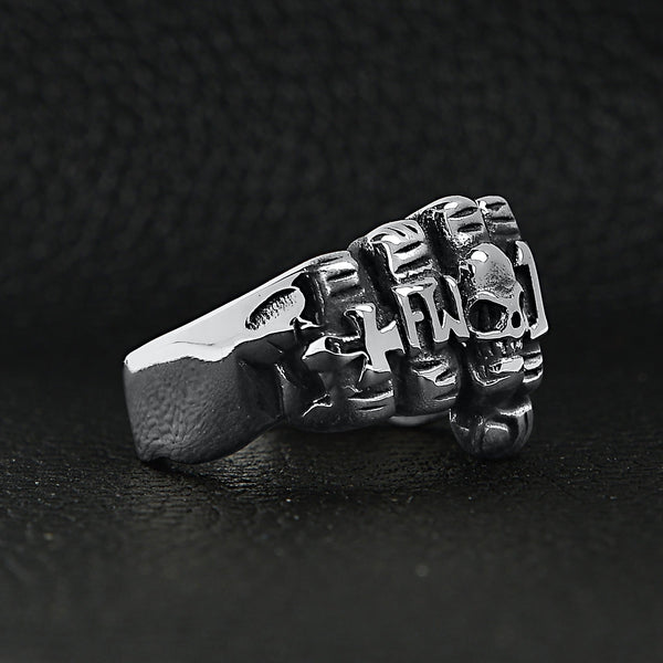 Stainless steel biker rings fist ring angled on a black leather background.