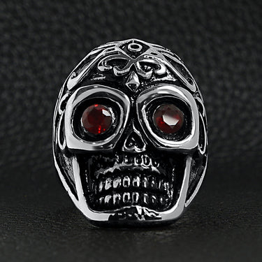 Stainless steel polished red Cubic Zirconia eyed filigree skull ring on a black leather background.