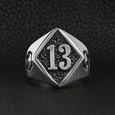 Stainless steel "13" and skulls ring on a black leather background.