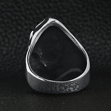 Stainless steel red Cubic Zirconia eyed grim reaper ring back view on a black leather background.