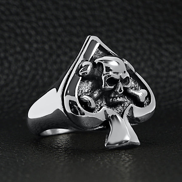 Stainless steel polished skull of spades ace ring angled on a black leather background.