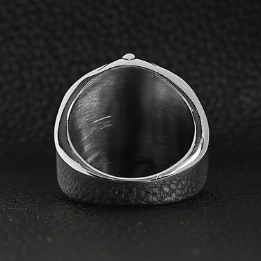 Stainless steel skull with spider and web accents ring back view on a black leather background.