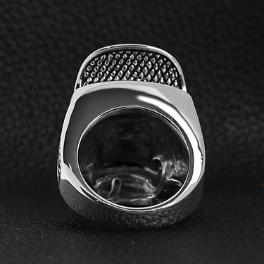 Stainless steel trucker hat skull ring back view on a black leather background.