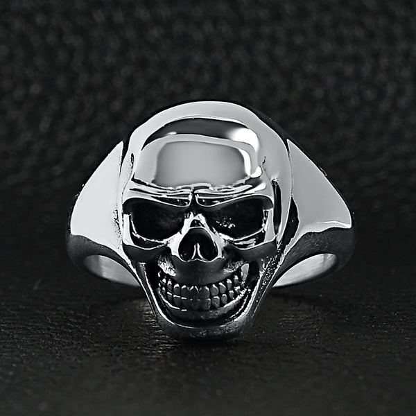 Stainless steel skull women's ring on a black leather background.