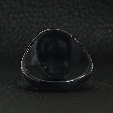 Stainless steel black skull ring back view on a black leather background.