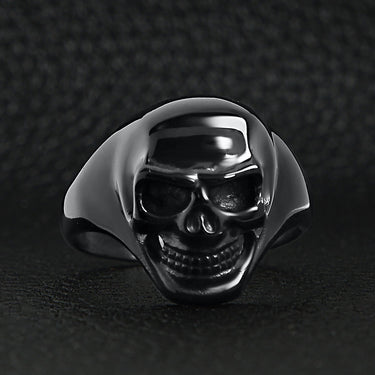 Stainless steel black skull ring on a black leather background.