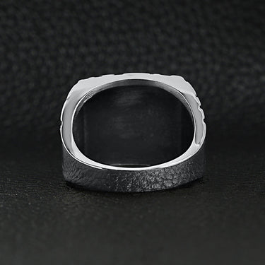 Stainless steel "BITCH" signet ring back view on a black leather background.