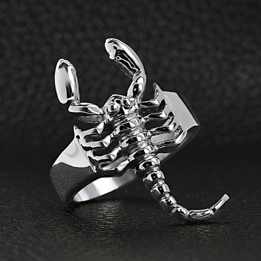 Stainless steel scorpion ring on a black leather background.