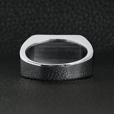 Stainless steel motorcycle club "MC" insignia signet ring back view on a black leather background.