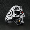 Stainless steel devil skull with red Cubic Zirconia eye smoking 18K gold PVD Coated cigar ring angled on a black leather background.