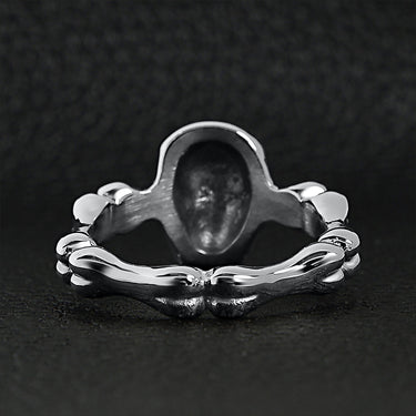 Stainless steel skull and bones women's ring back view on a black leather background.