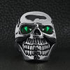 Stainless steel green Cubic Zirconia eyed cracked skull ring on a black leather background.
