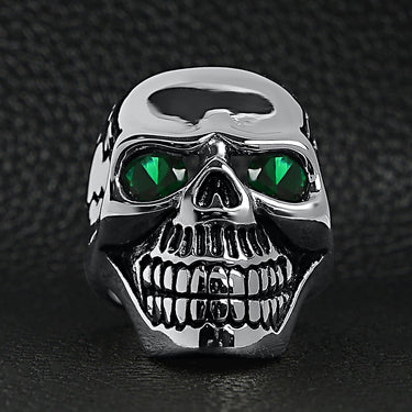 Stainless steel green Cubic Zirconia eyed cracked skull ring on a black leather background.