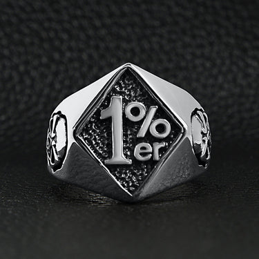 Stainless steel "1%er" with skull accents signet ring on a black leather background.