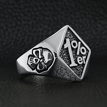 Stainless steel "1%er" with skull accents signet ring angled on a black leather background.