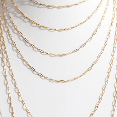 Gold chain necklaces stacked on a white background
