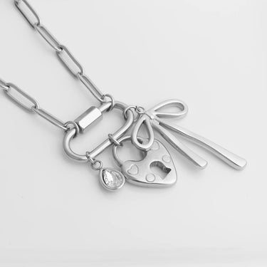 Silver necklace with various charms on a light gray background