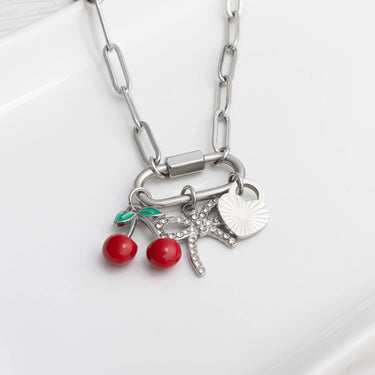 Silver necklace with cherry and leaf charms on a white background