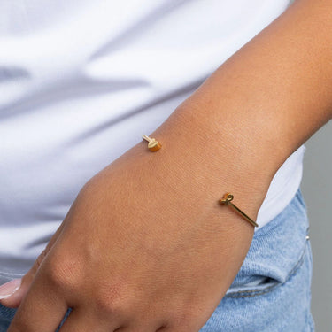 Gold Adjustable Cuff with Cancer Ribbon Charm GIft Set on a wrist with a blurred background