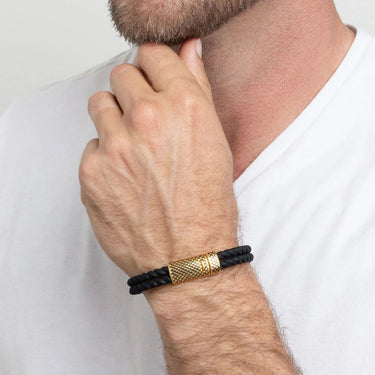 Man wearing a black and gold Rubber Metal Clasp Bracelet Gift Set on a white background