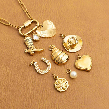 Collection of gold charms including a boot, horse, heart, and compass on a brown background.