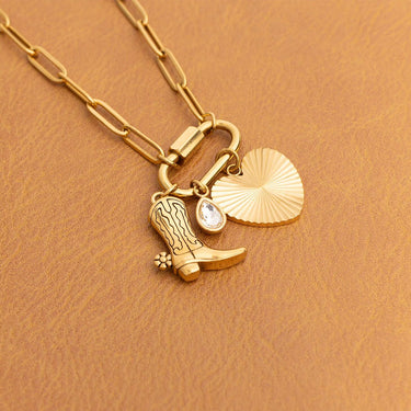 Gold necklace with a boot and shell charm on a brown background