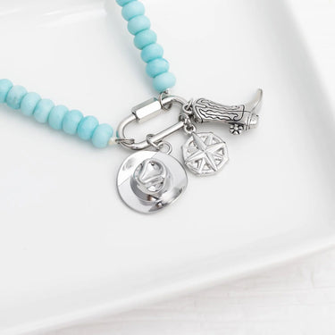 Turquoise beaded necklace with silver charms on a white background