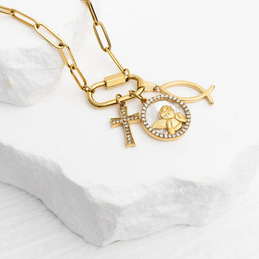 Gold necklace with charms on a white fabric background