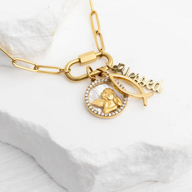 Gold bracelet with angel, fish, and 'Hered' charm on a white fabric background