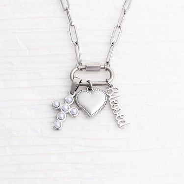 Silver necklace with heart, cross, and 'blessed' charm on a white background
