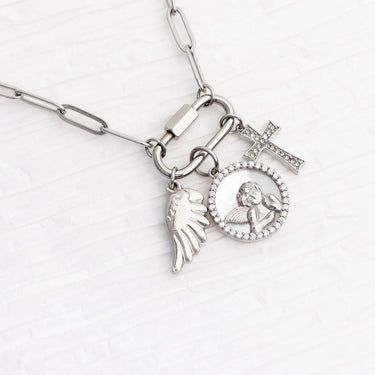 Silver necklace with angel, cross, and round charm on a white background