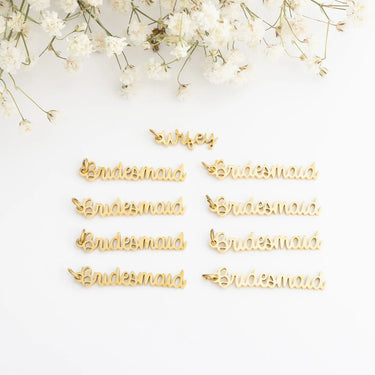 Gold 'Bridesmaid' pins on a white background with baby's breath flowers.