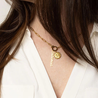 Gold necklace with a pendant on a person wearing a white shirt