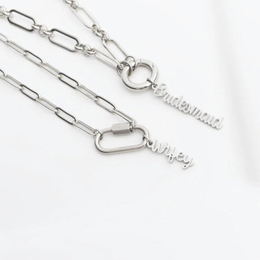 Silver necklaces with 'Bridesmaid' and 'Wifey' charms on a white background