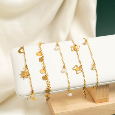 Gold bracelets with star and moon designs on a white stand.