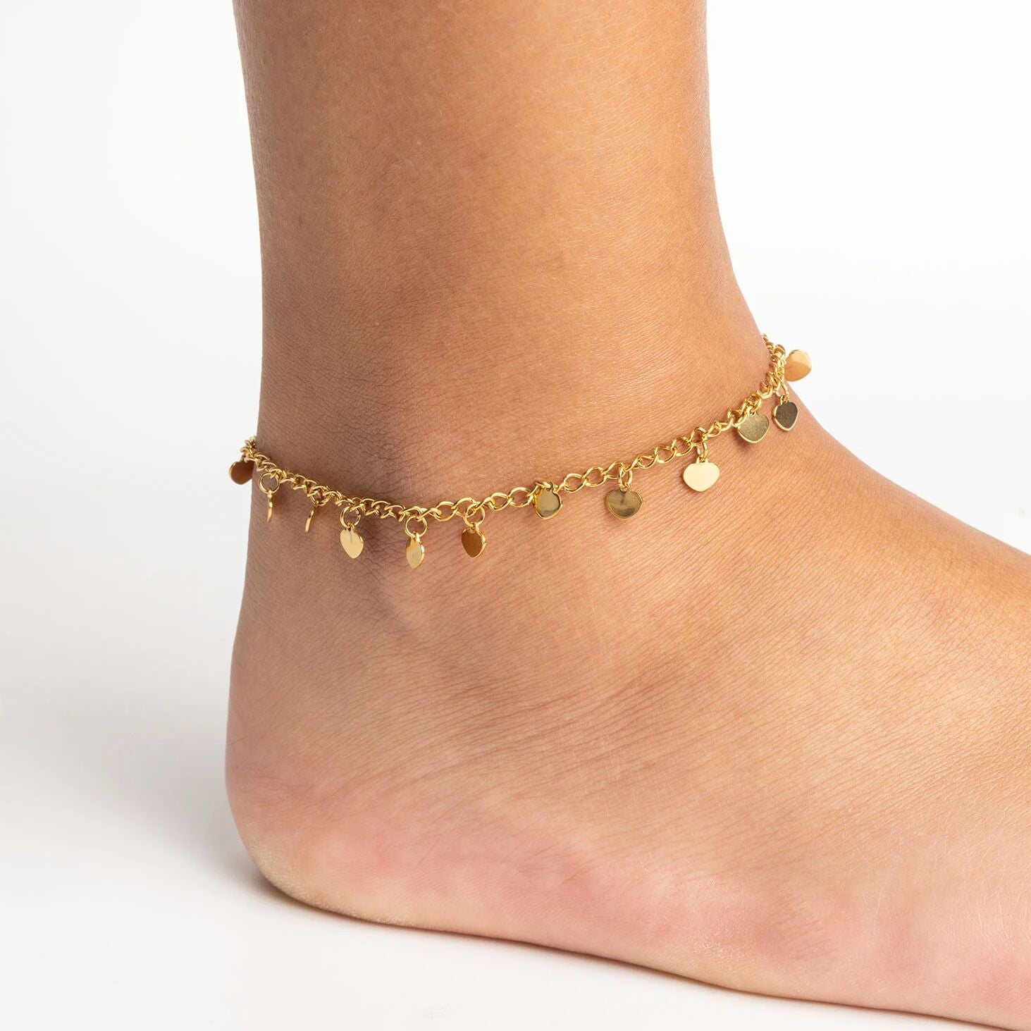 Gold Dangle Hearts Anklet on a foot against a neutral background