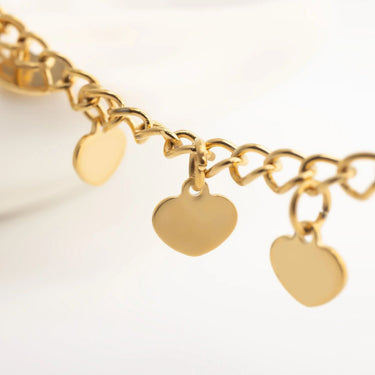 Gold anklet with heart-shaped charms on a light background