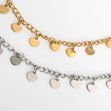 Two gold and silver heart-shaped charm anklet on a light gray background