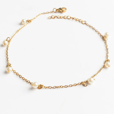 Gold anklet with pearls on a white background