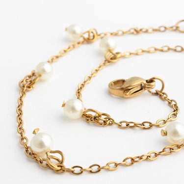 Gold chain bracelet with pearls on a white background