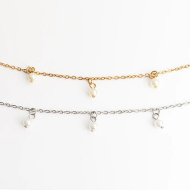 Two gold necklaces with small pearls on a white background