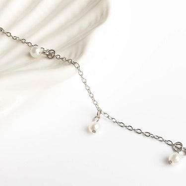 Silver chain necklace with pearls on a white background